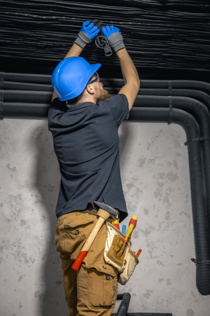 electrician installing laying electrical cables ceiling inside house
